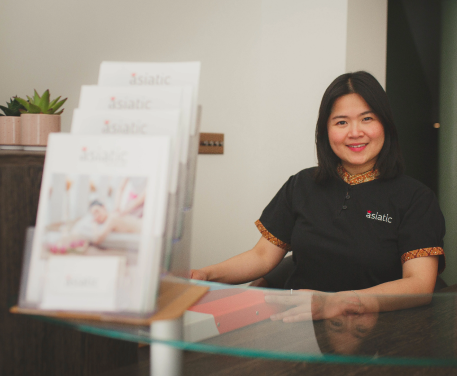 Smiling Thai receptionist at Asiatic, eagerly anticipating the arrival of a new client.