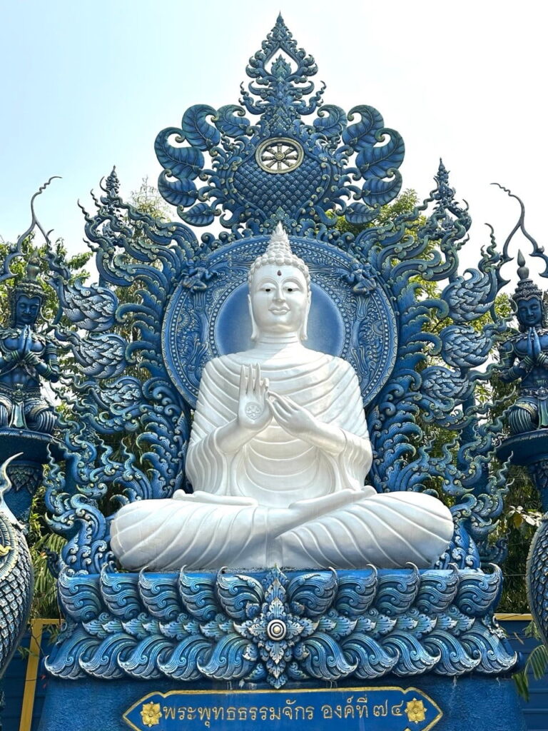 Cross-legged Buddha deity inside a blue temple in Chiang Rai reflecting Thai spiritual and meditative traditions.