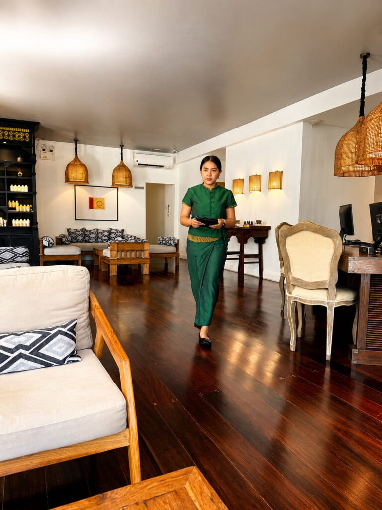 Thai massage therapist walking through the welcoming reception area of Oasis Spa in Bangkok.