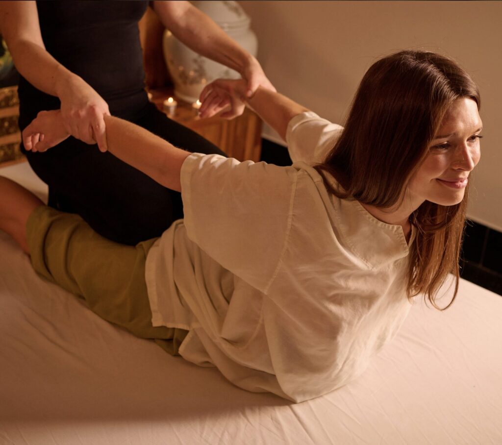 London-based Thai massage therapist performing cobra stretching yoga on a client.