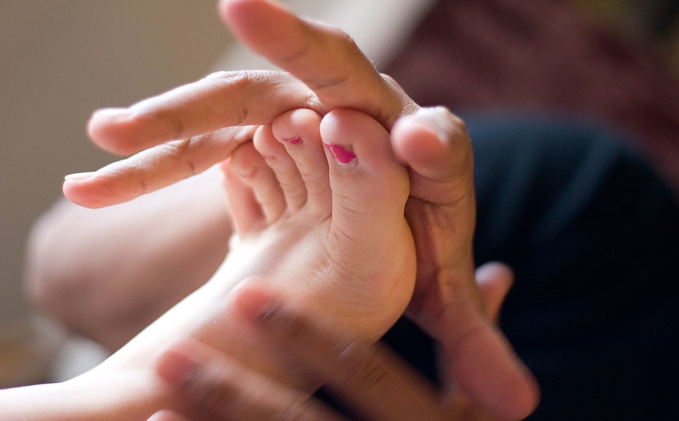 Professional therapist providing a Thai foot massage on a client, promoting relaxation and well-being