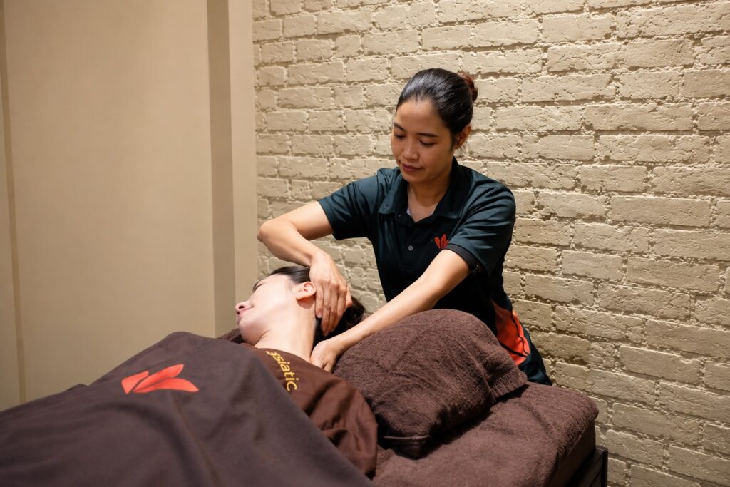 Asiatic massage therapist performing Thai neck stretching technique in London.