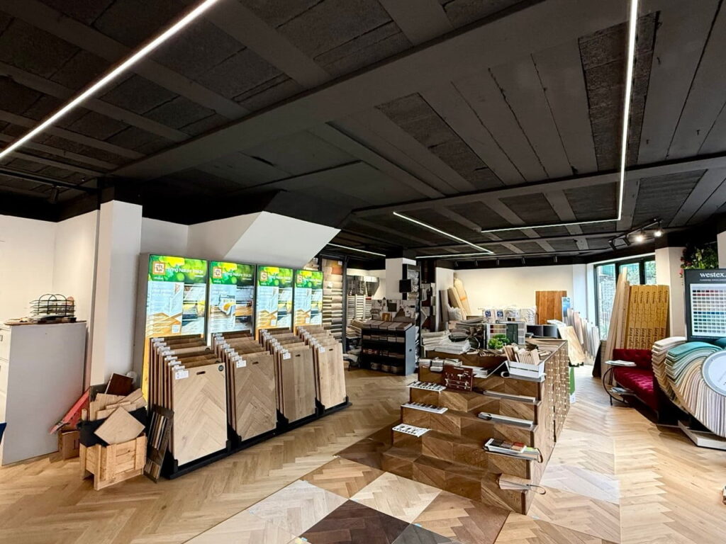 The newly renovated minimalist showroom of Lee Banks Carpets at N75 Essex Road Islington, featuring modern flooring displays and architectural lighting.