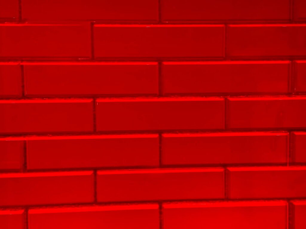 An architectural red brick wall integrated with translucent glass blocks, serving as a structural metaphor for breaking down stubborn muscle knots and restoring transparency at Asiatic Thai Massage in Islington, London