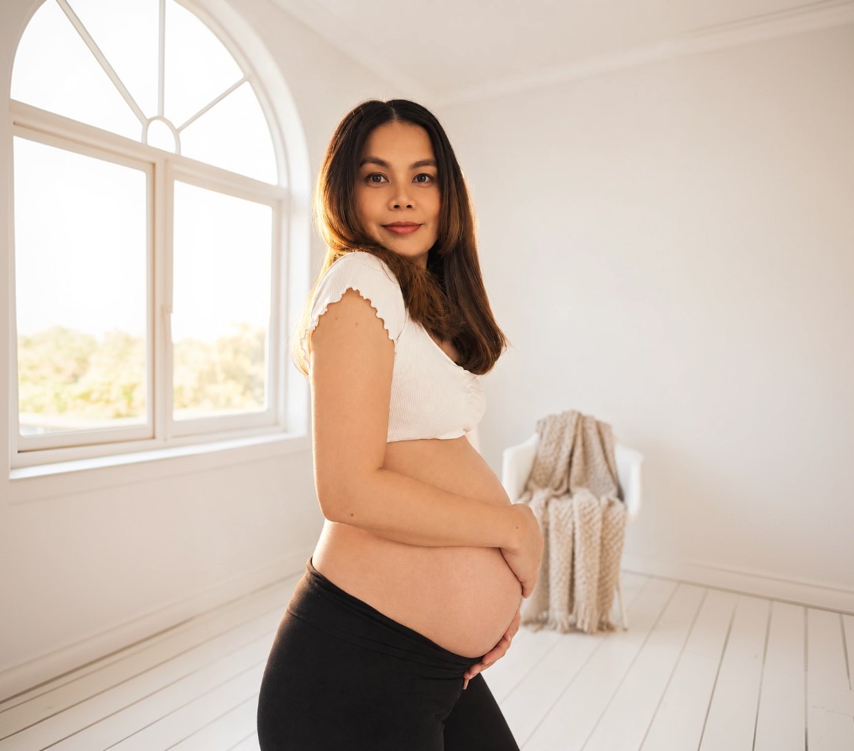 Smiling pregnant woman standing in a bright room
