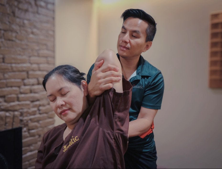 Therapist guiding an assisted arm stretch during Thai Yoga Massage